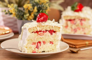 a piece of cake with white frosting and strawberries on top